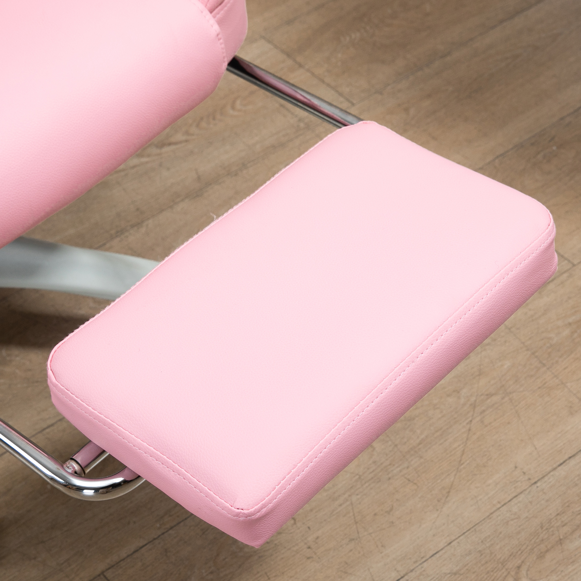 Nahaufnahme einer rosa Fußstütze auf einem Metallrahmen. Die Fußstütze ist gepolstert und hat Nahtdetails.