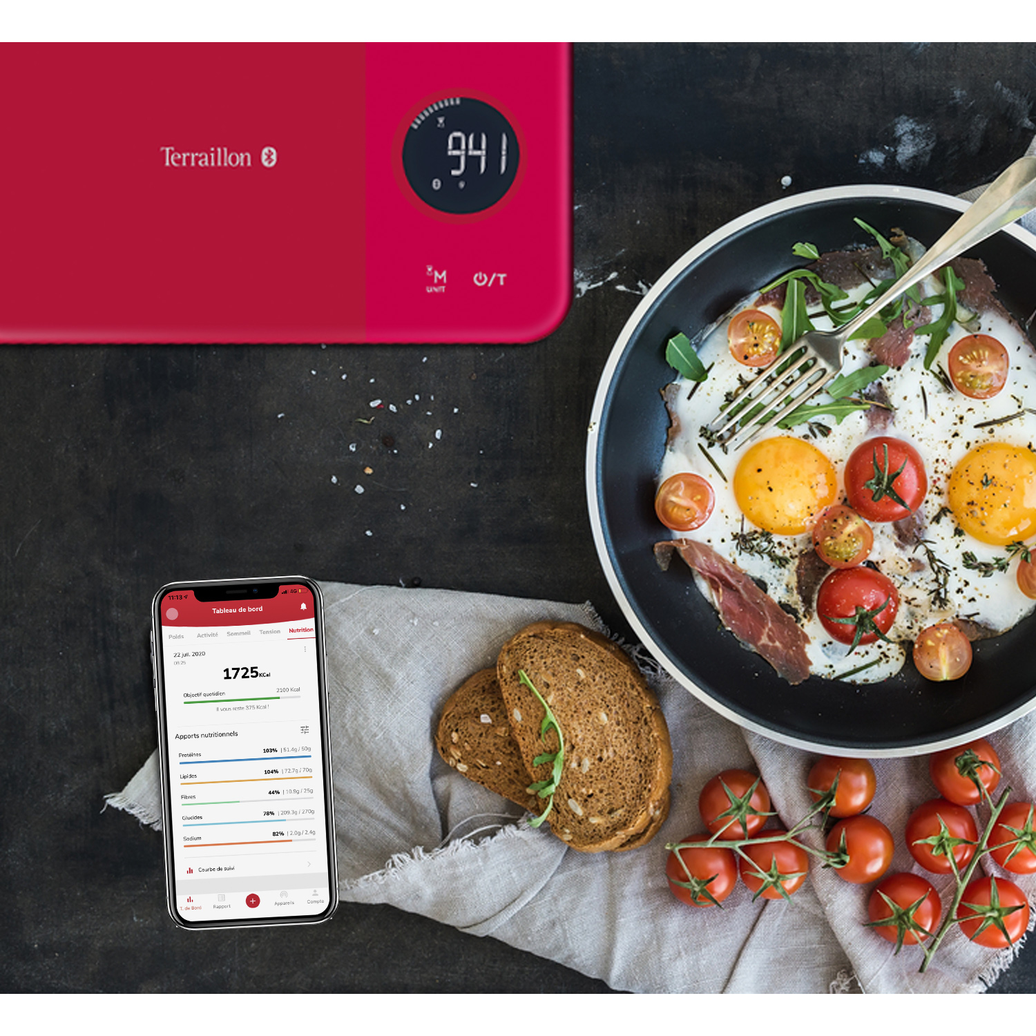 Waga kuchenna, jajka sadzone, pomidory, chleb i telefon wyświetlający informacje o wartości odżywczej.