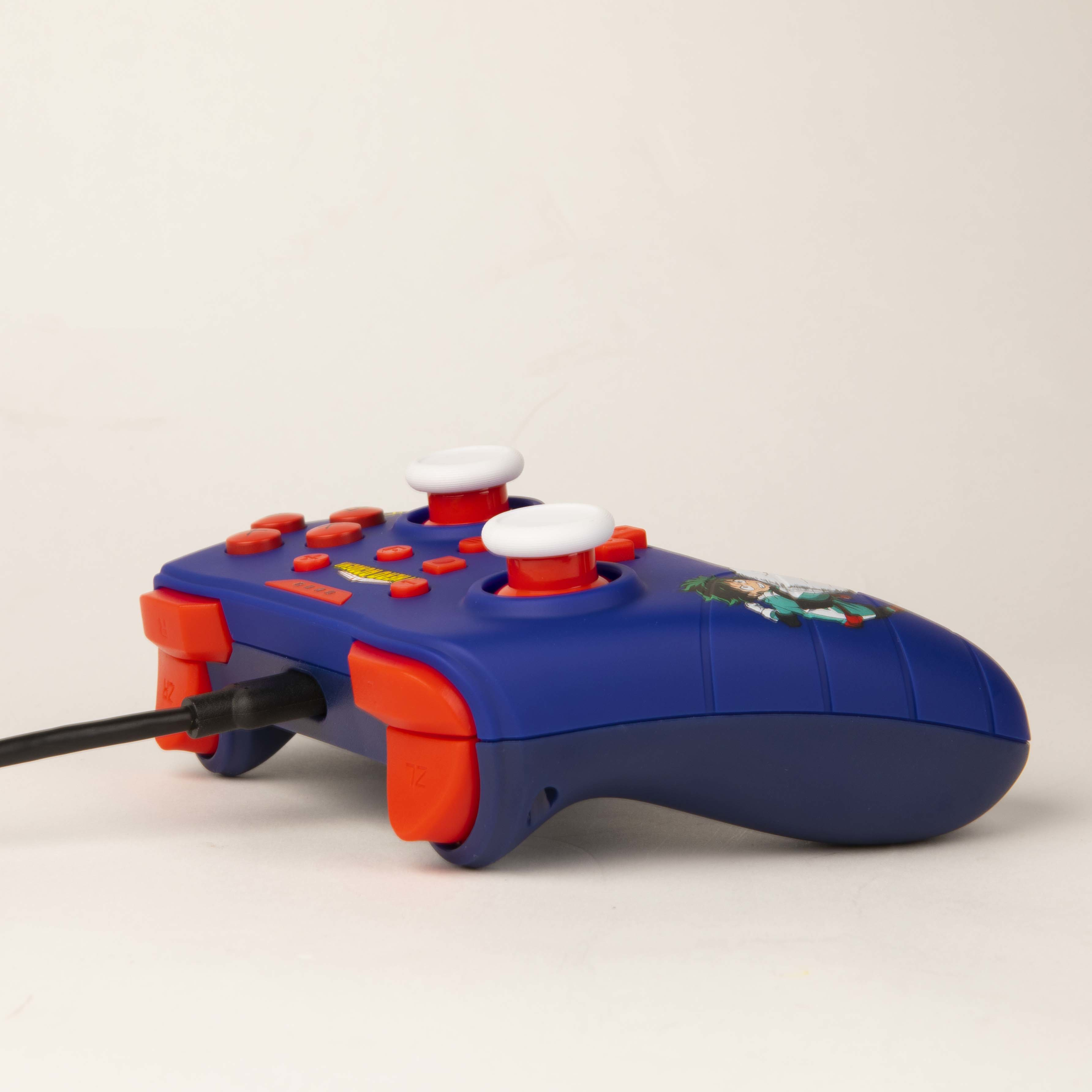 Controller per videogiochi blu e rosso con joystick bianchi. Il controller è su una superficie bianca.
