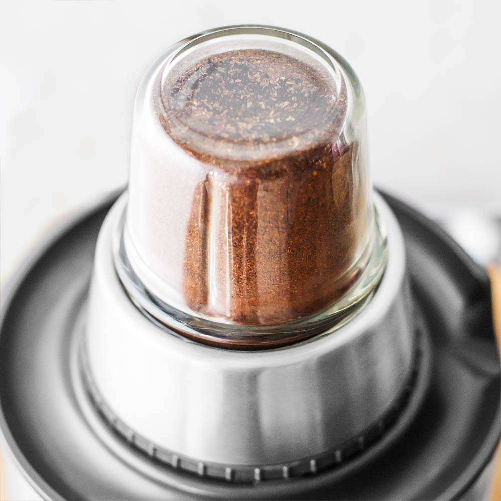 Kaffeemühle mit Kaffeepulver. Silbernes und gläsernes Design.
