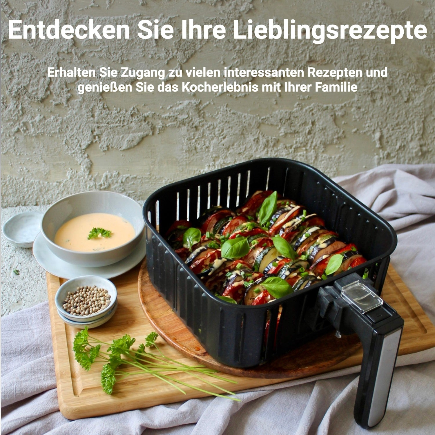 Heißluftfritteuse mit Essen, mit Schalen und Holzbrett. Text: Entdecken Sie Ihre Lieblingsrezepte.