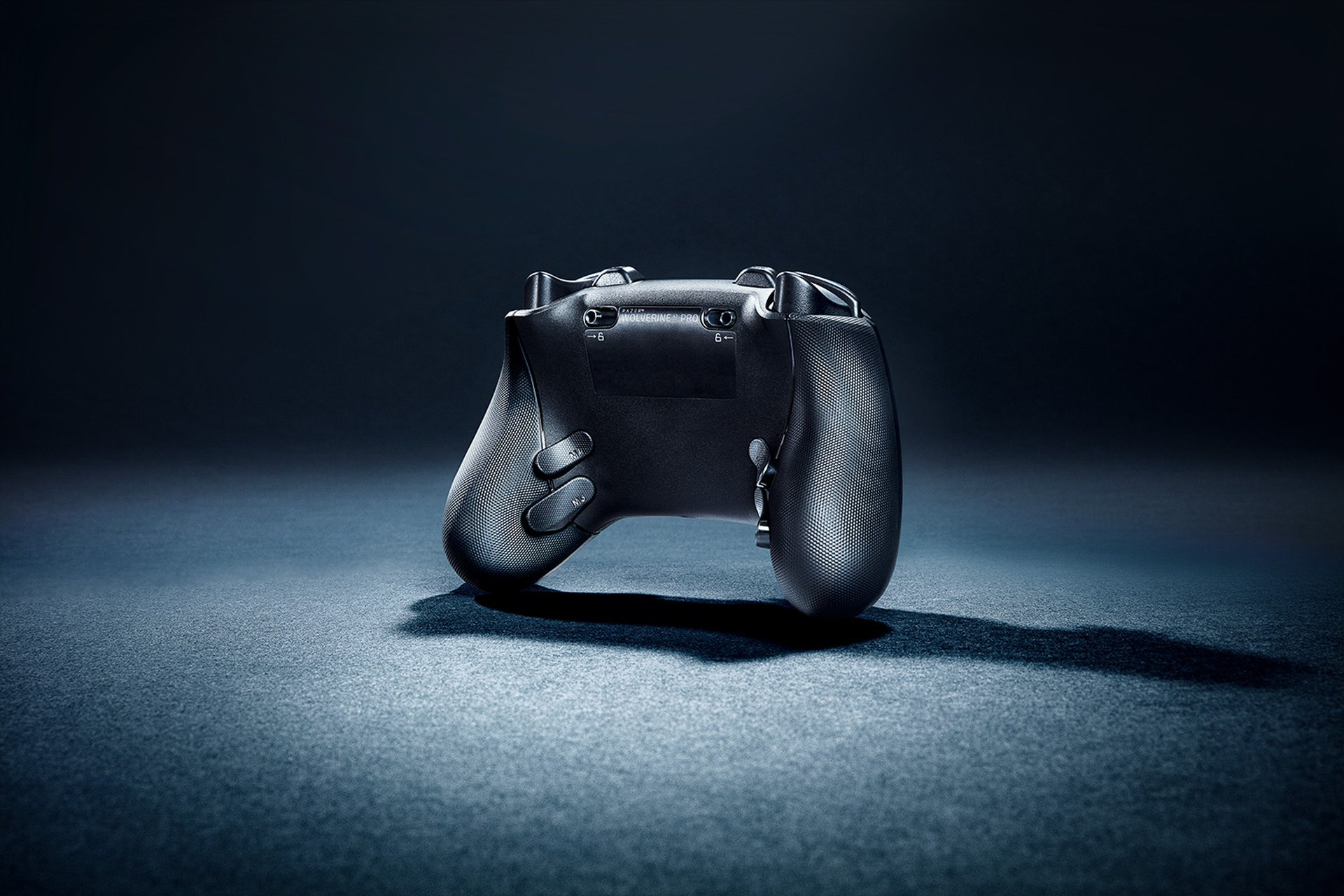 Czarny kontroler do gier widziany od tyłu, umieszczony na ciemnej powierzchni.