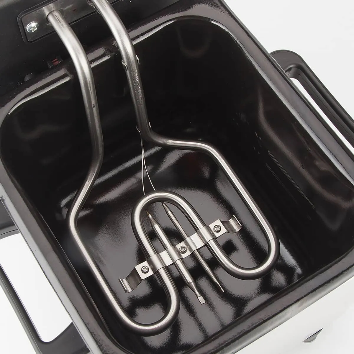 Zbliżenie frytkownicy. Metalowe elementy grzejne w czarnym pojemniku.