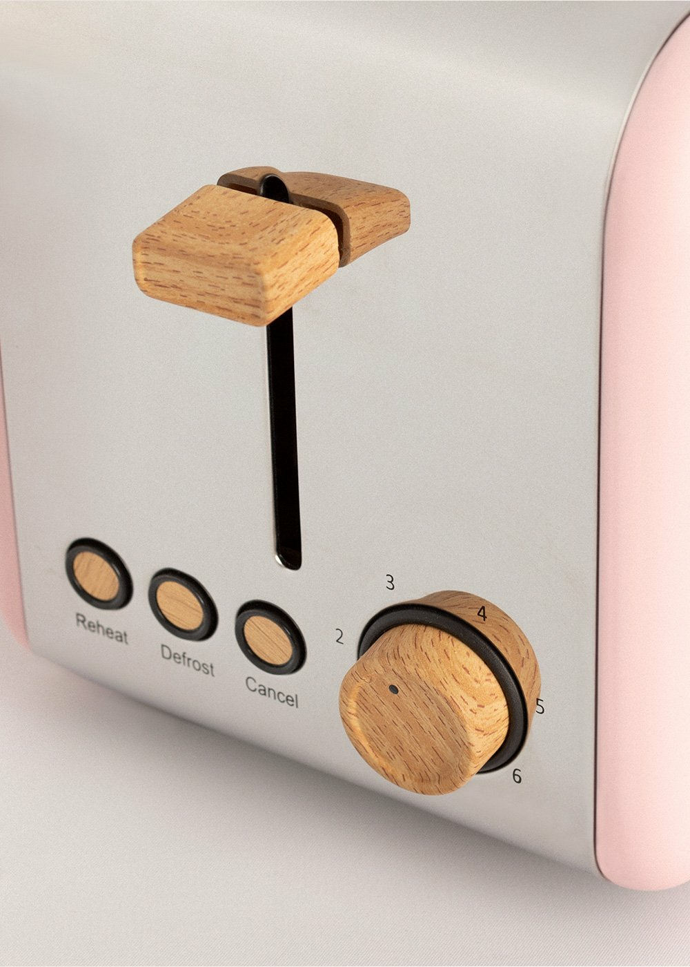 Primer plano de una tostadora rosa y plateada con detalles de madera.