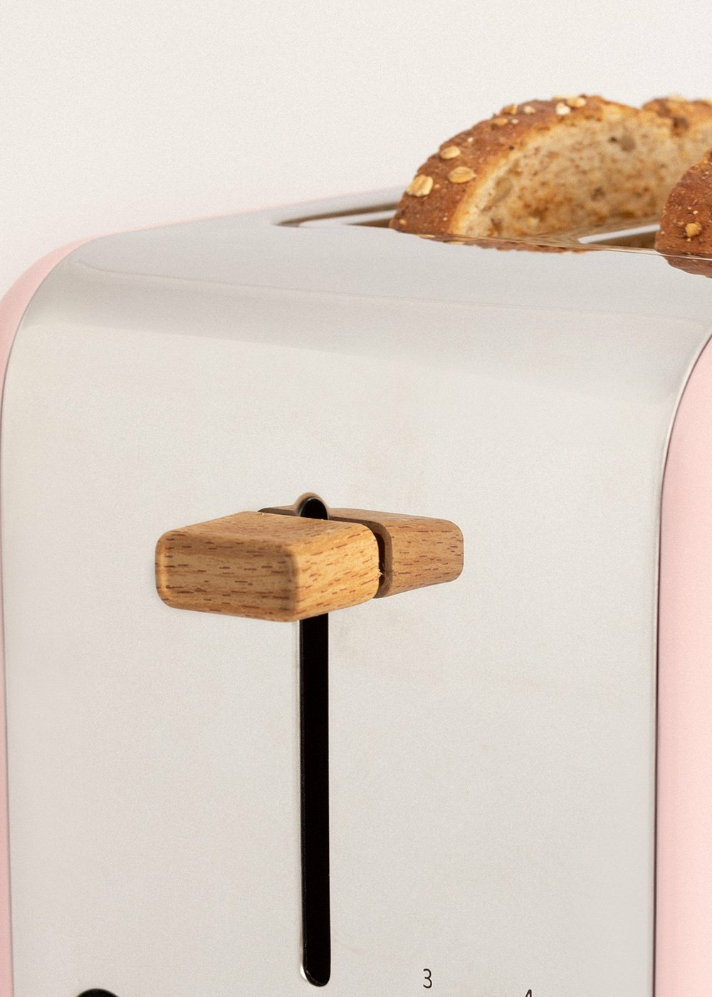 Primer plano de una tostadora rosa y plateada con dos rebanadas de pan tostado.