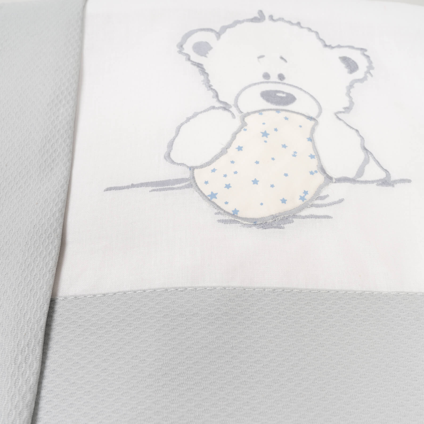 Manta de bebé blanca y gris con diseño de oso de peluche.