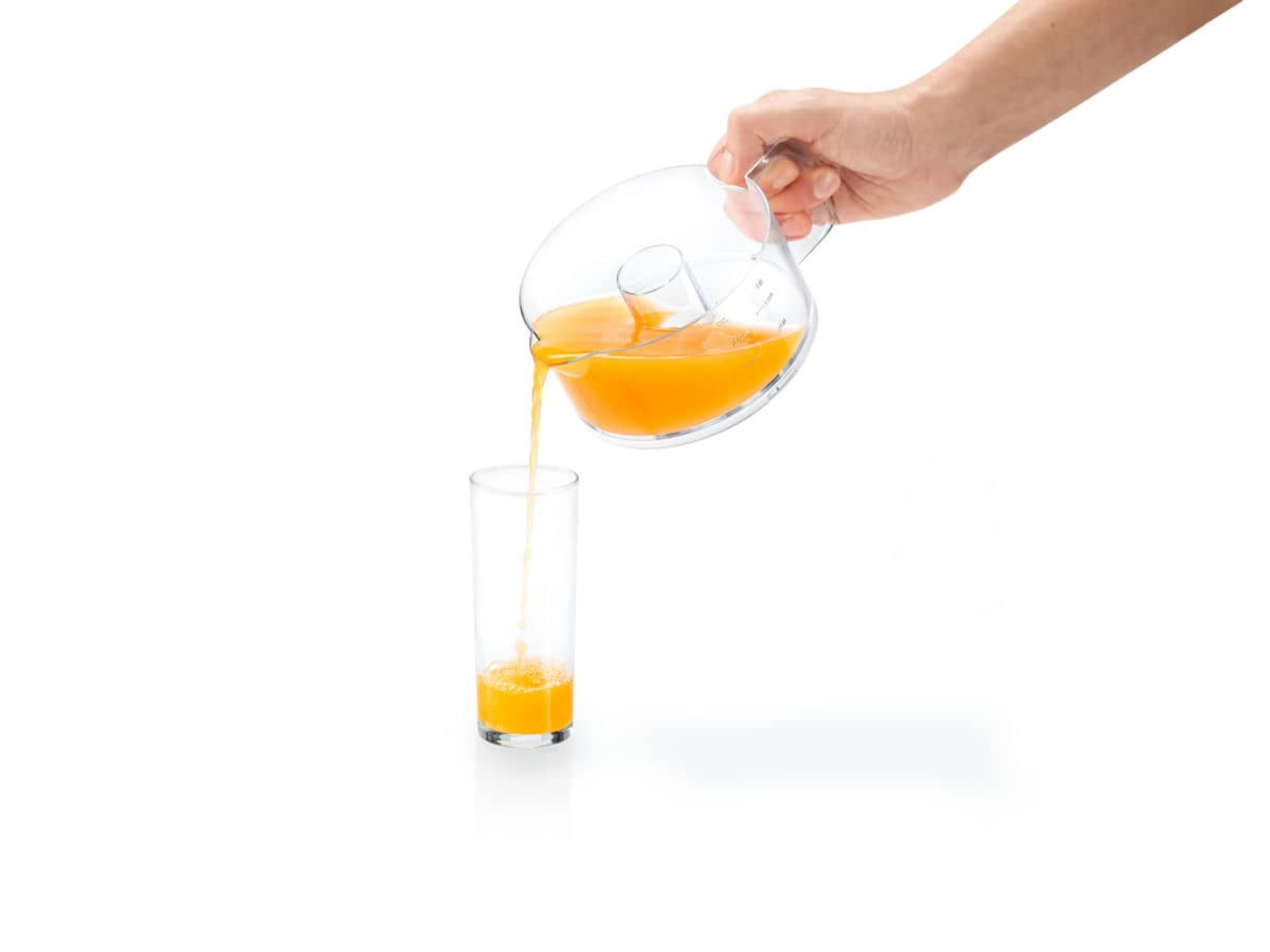 Ręka nalewająca sok pomarańczowy z dzbanka do szklanki. Białe tło.