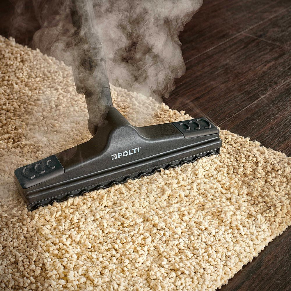 Głowica parownicy na beżowym dywanie. Para unosi się w górę. Czyszczący jest oznaczony 'POLTI'.