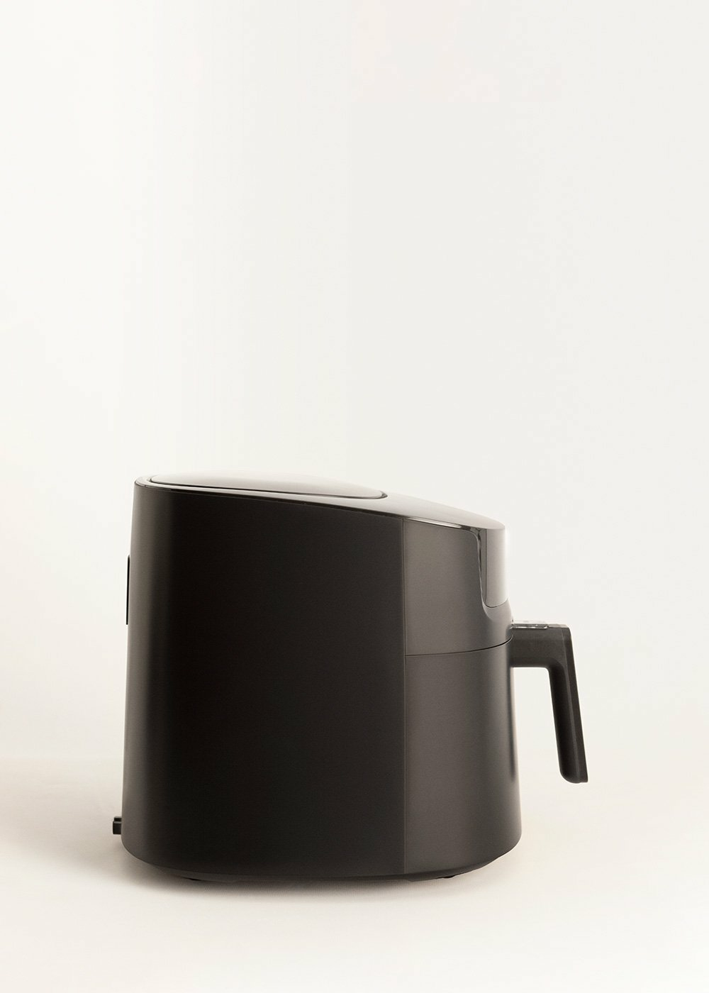 Czarna frytkownica beztłuszczowa na białym tle. Ma uchwyt z boku.