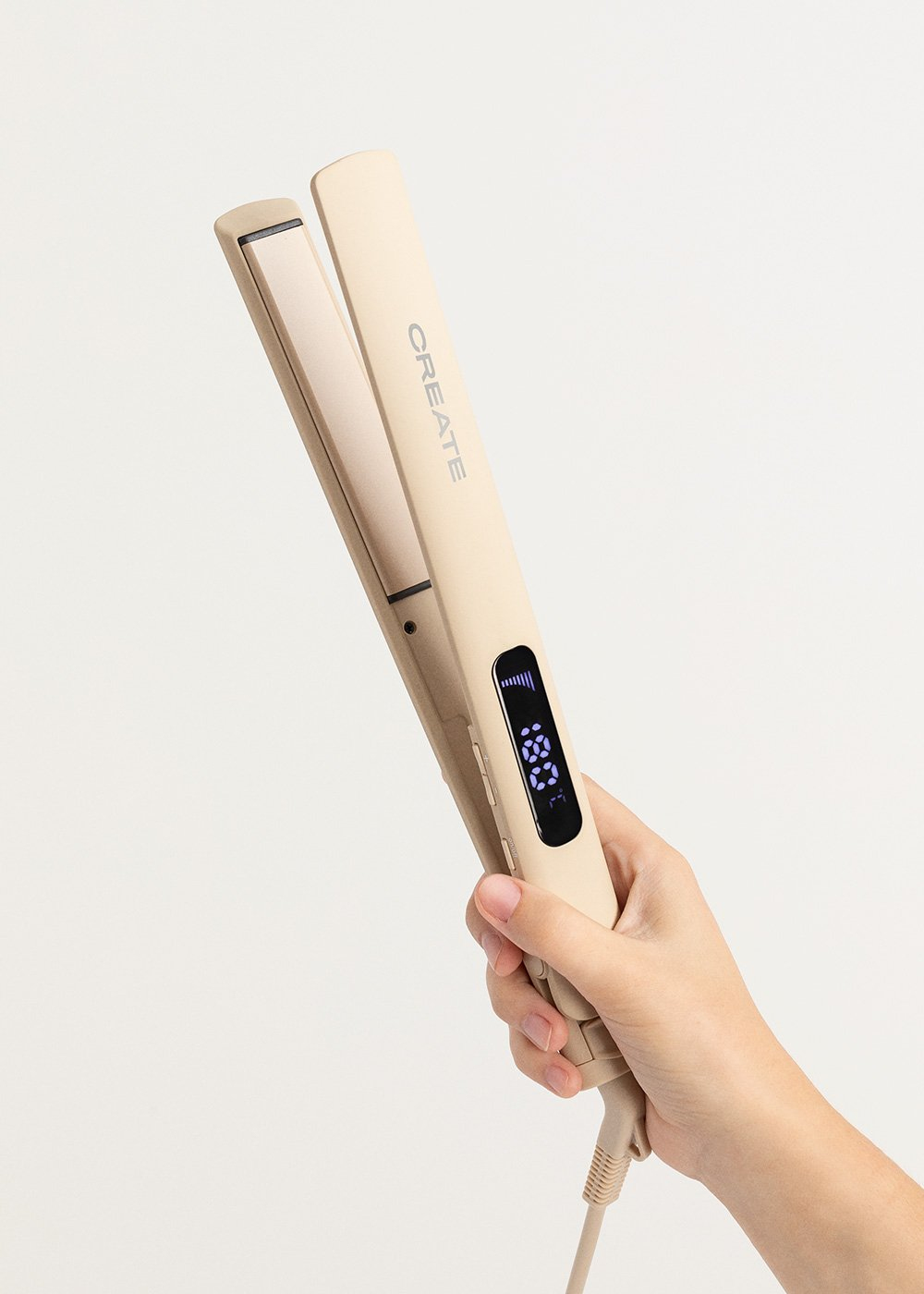 Una mano sosteniendo una plancha de pelo beige con pantalla digital.
