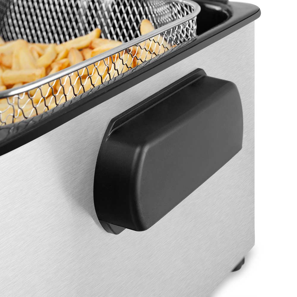 Primer plano de una freidora. Una cesta de patatas fritas está dentro. Mango negro lateral.