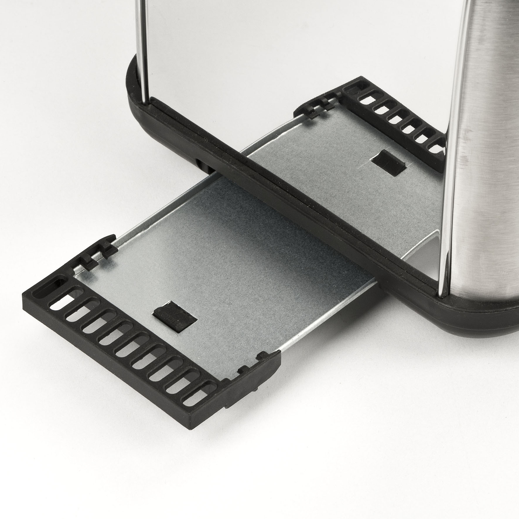 Tacka na okruchy z tostera jest wysunięta. Toster jest ze srebra i czarnego plastiku.