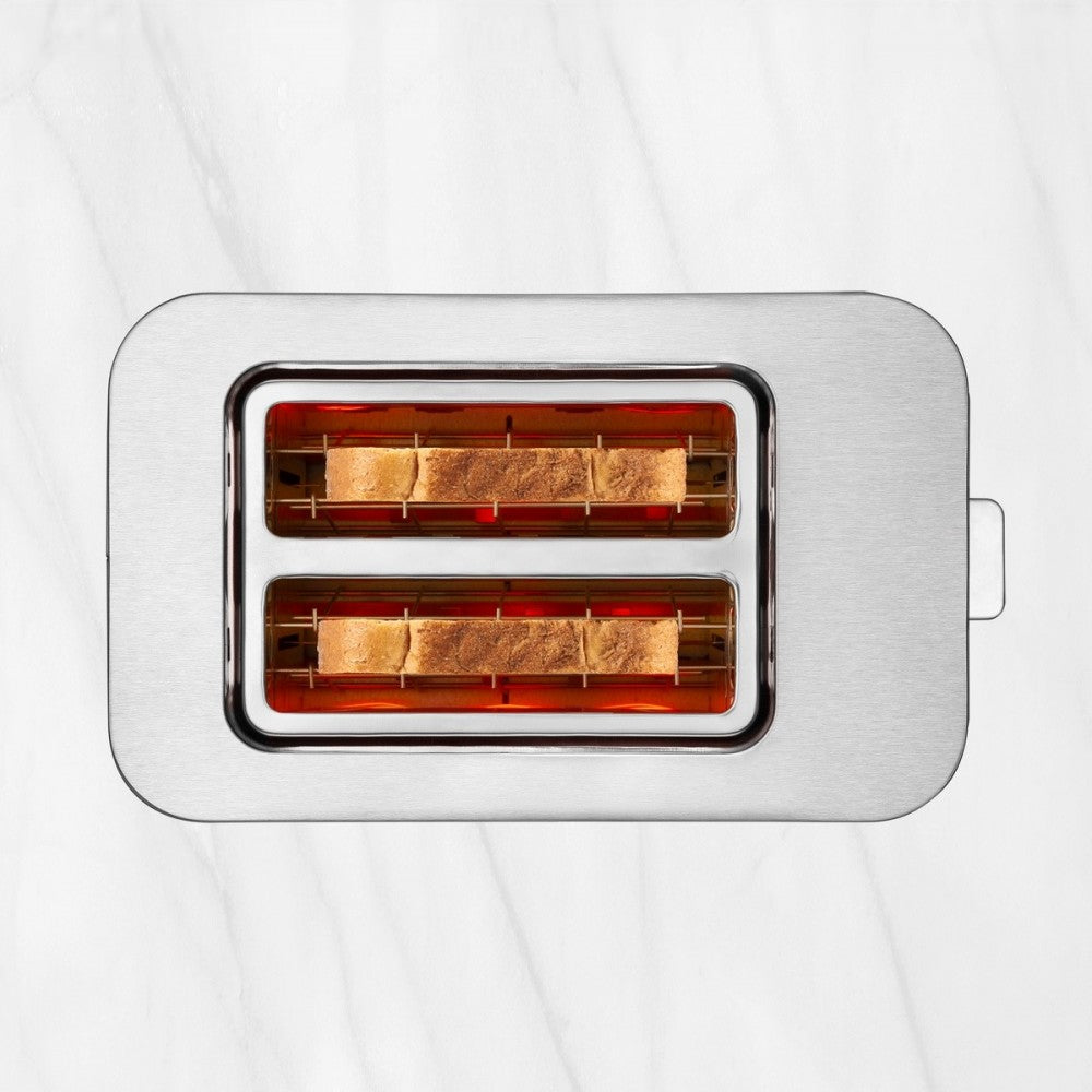 Toster ze stali nierdzewnej z dwoma kromkami tostów w środku. Stoi na białej marmurowej powierzchni.