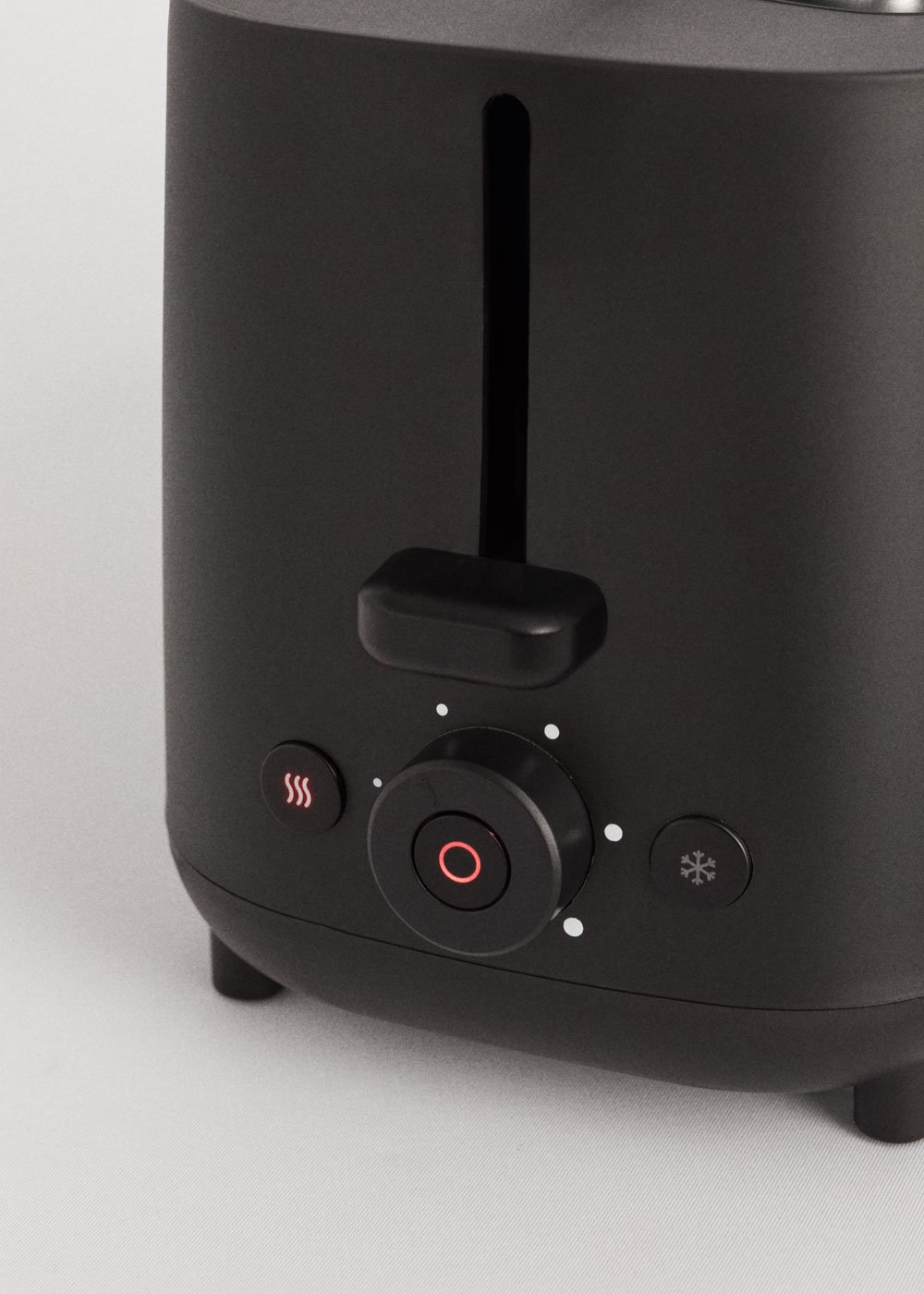Un grille-pain noir avec un bouton de commande, des boutons et une fente, gros plan.