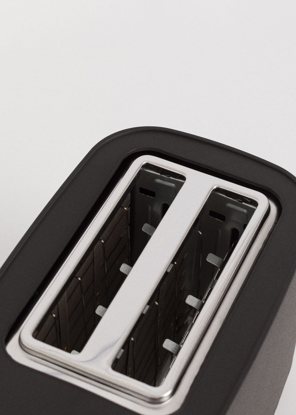Gros plan sur un grille-pain noir. Deux fentes sont visibles. L'intérieur est argenté. Le fond est blanc.