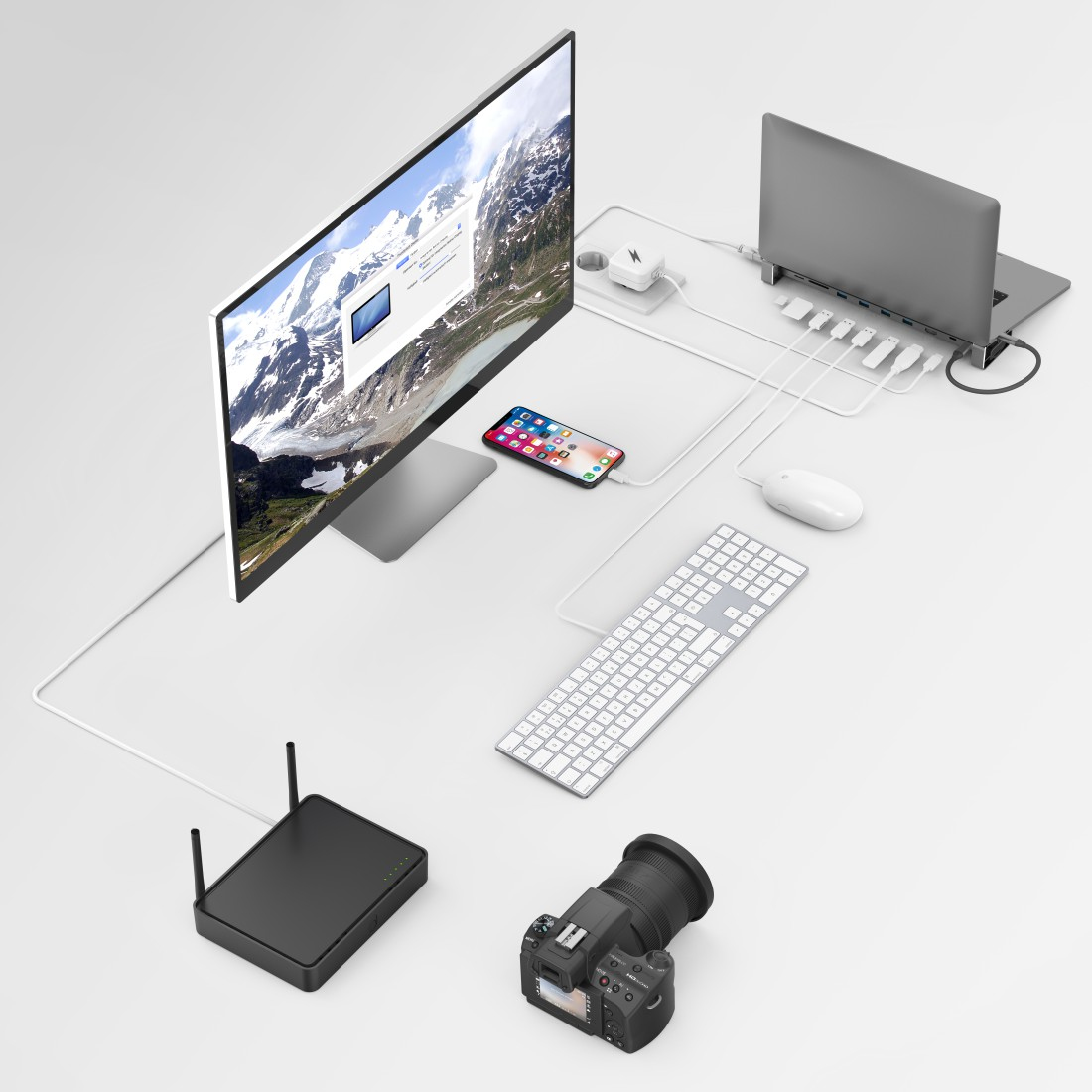 Ein Schreibtisch-Setup mit Monitor, Laptop, Telefon und Zubehör. Ein Berg-Hintergrund ist auf dem Monitor.