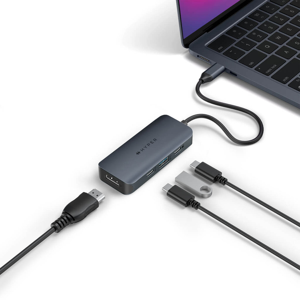 Un hub grigio con un laptop, collegato tramite cavo. Sono collegati anche altri cavi: USB-C, HDMI e USB. Il marchio è HYPER.