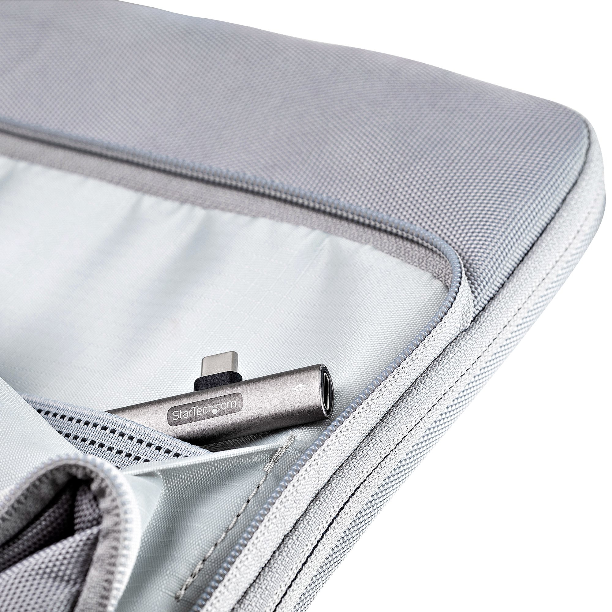 Adaptador de audio USB-C a 3,5 mm plateado en una funda gris. La funda está en una bolsa gris.