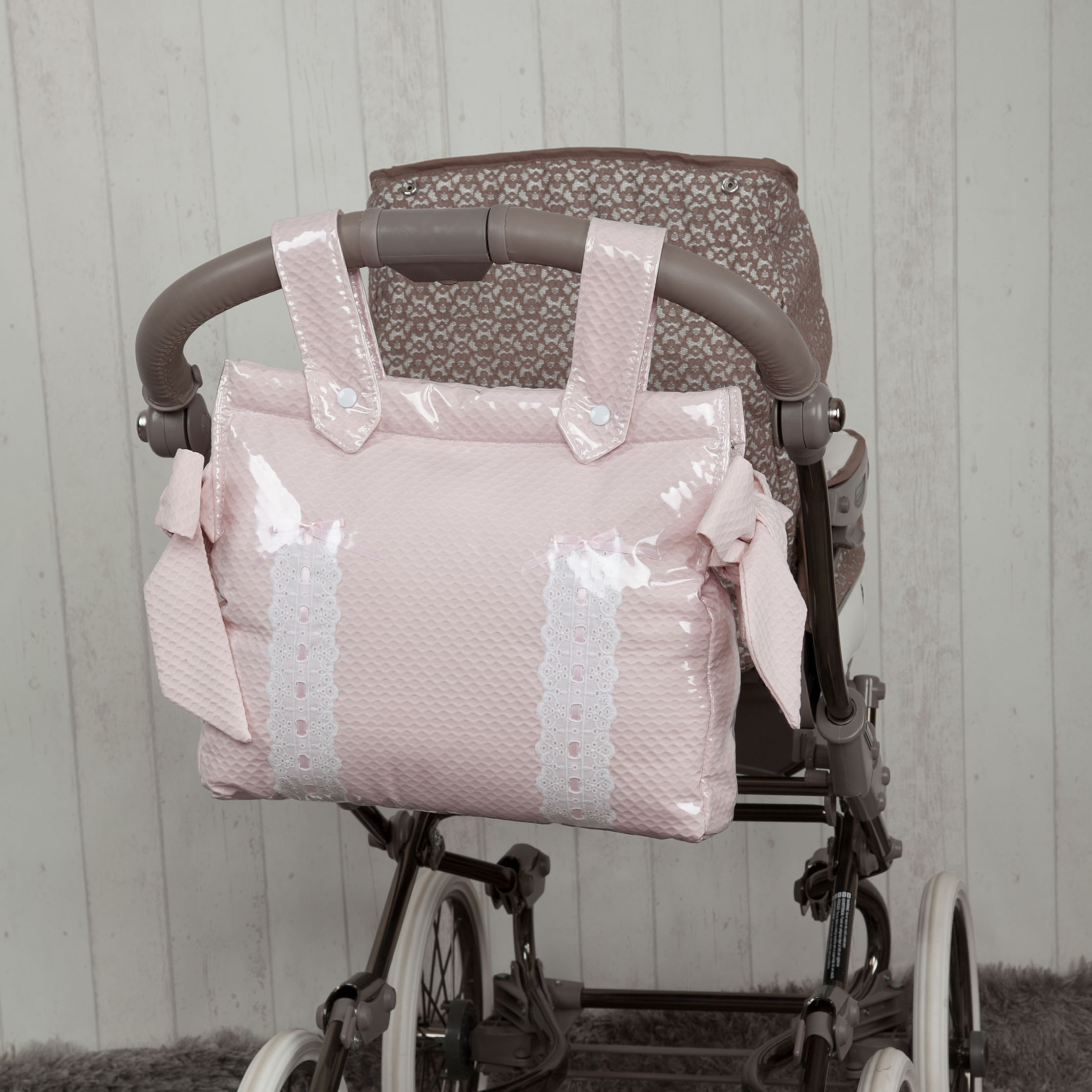 Bolso rosa para bebé en un cochecito. Fondo claro con pared estampada.