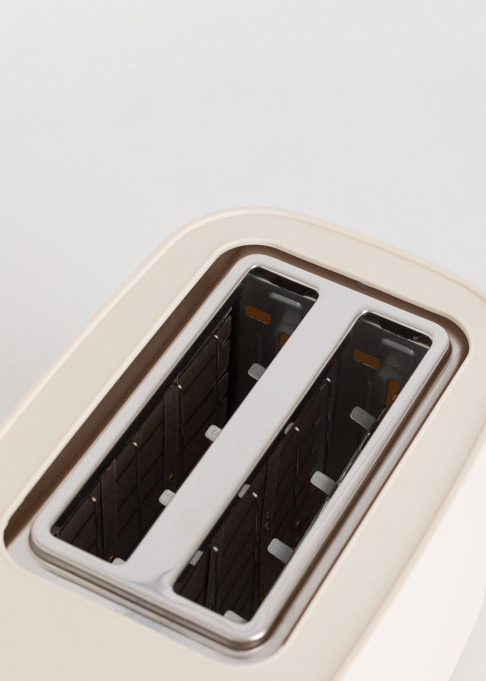 Un grille-pain blanc avec deux fentes. Les fentes sont noires à l'intérieur. Le grille-pain est en gros plan.