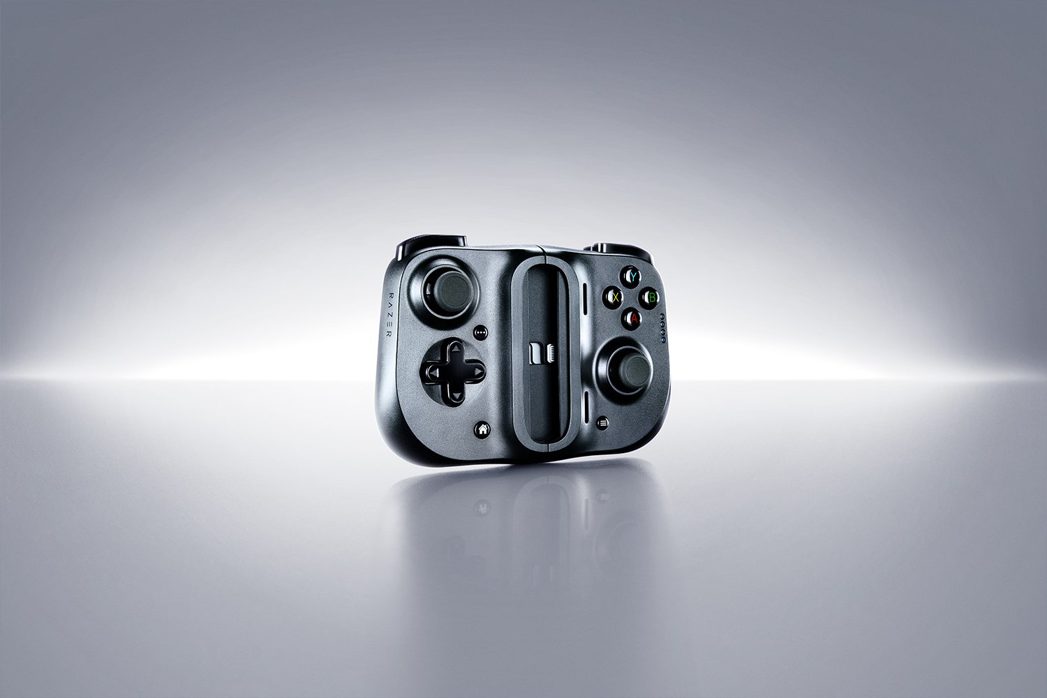 Ciemnoszary kontroler gier z przyciskami i gałkami analogowymi. Na jasnoszarej powierzchni.