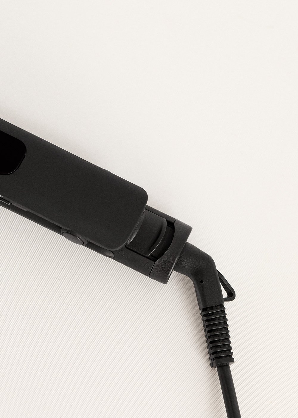 Plancha de pelo negra, vista de cerca de las placas calefactoras y el cable de alimentación.