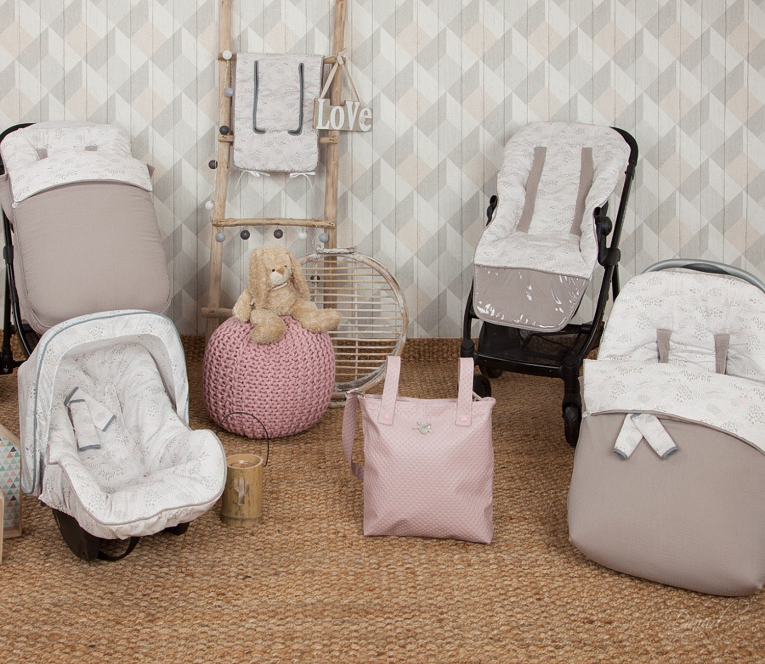 Artículos de bebé: cochecito, asiento de coche, bolsos y ropa de cama, en una habitación con papel tapiz y alfombra.