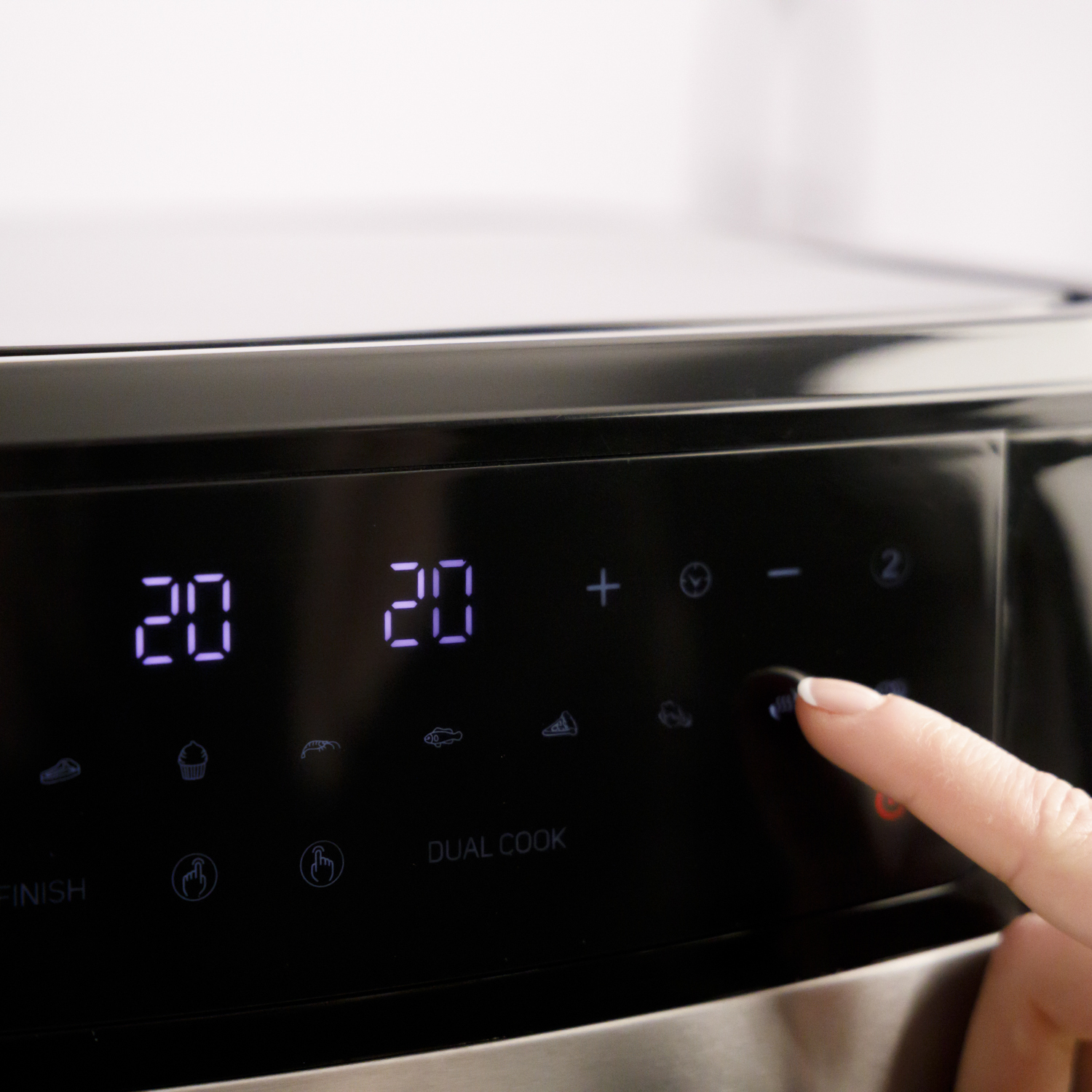 Zbliżenie wyświetlacza urządzenia pokazującego liczby 20 i 20. Palec dotyka przycisku.