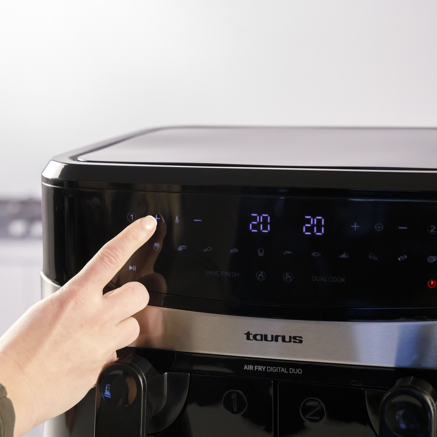 Ręka naciska przycisk na czarno-srebrnej frytkownicy, pokazując ustawienia czasu.