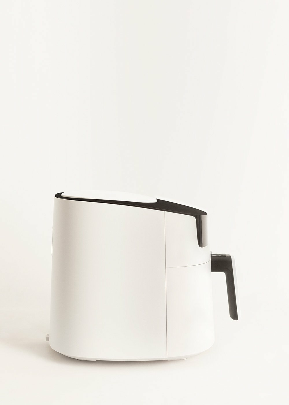 Biała frytkownica powietrzna z czarnym uchwytem na białym tle. Minimalistyczny design, nowoczesny sprzęt kuchenny.