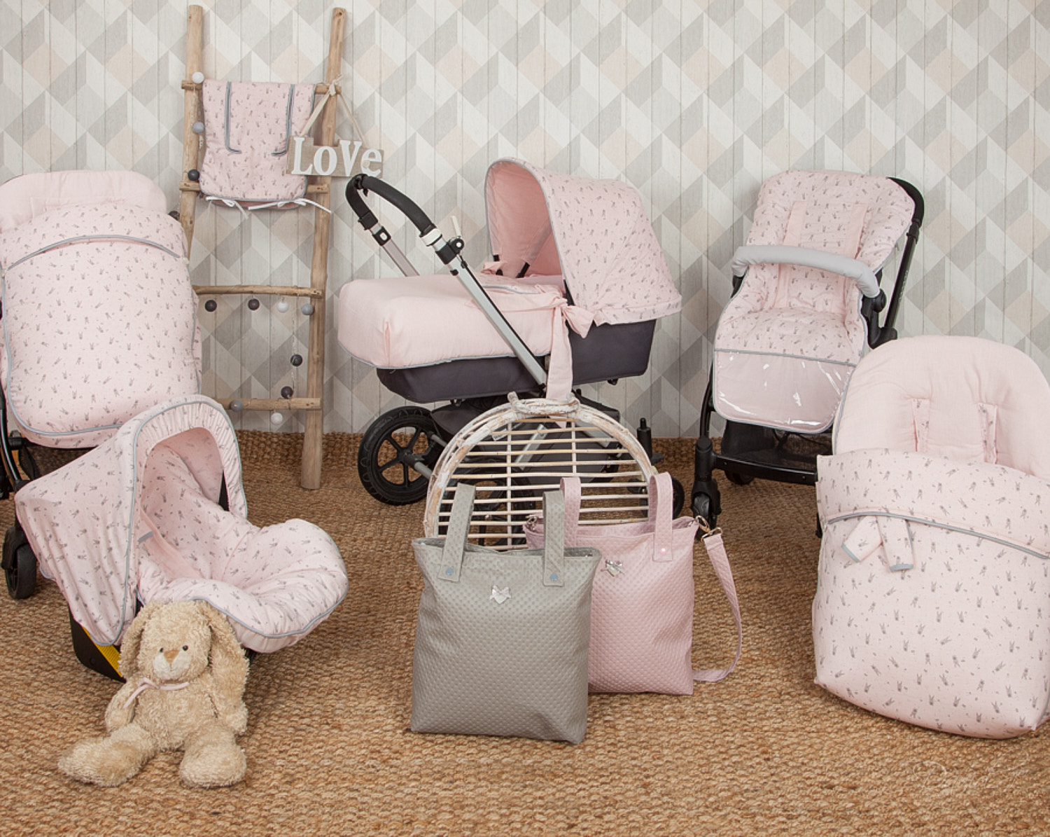 Juego de cochecito de bebé rosa con estampado de conejos, incluye transportín, bolsos y peluche.