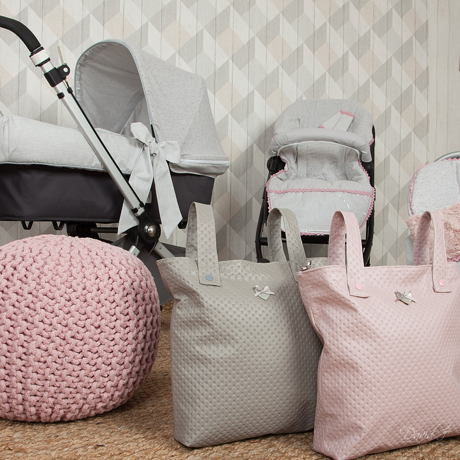 Artículos para bebés: cochecito, bolsos, otomana rosa, colores gris y rosa suaves.