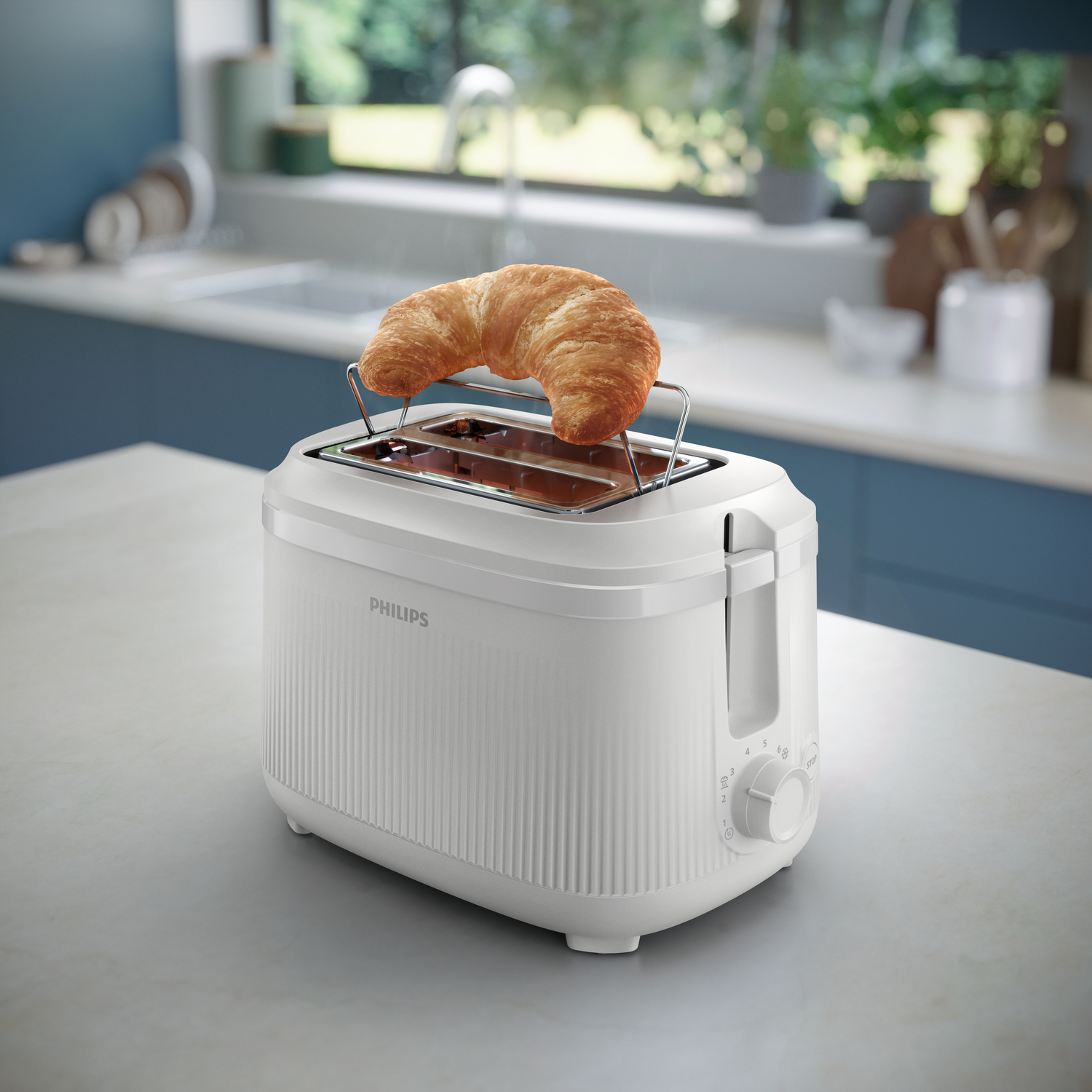 Weißer Philips-Toaster mit Croissant. Küchenhintergrund mit blauen Schränken ist sichtbar.