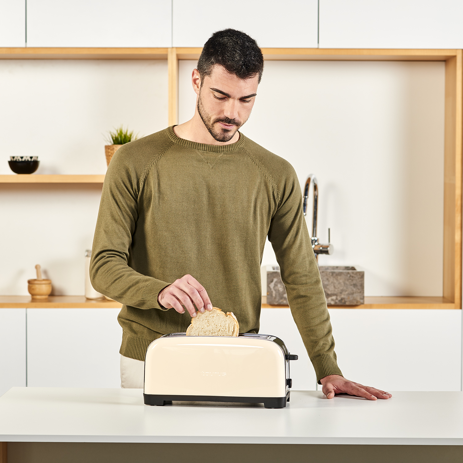 Uomo che mette il pane in un tostapane beige. Sfondo cucina.