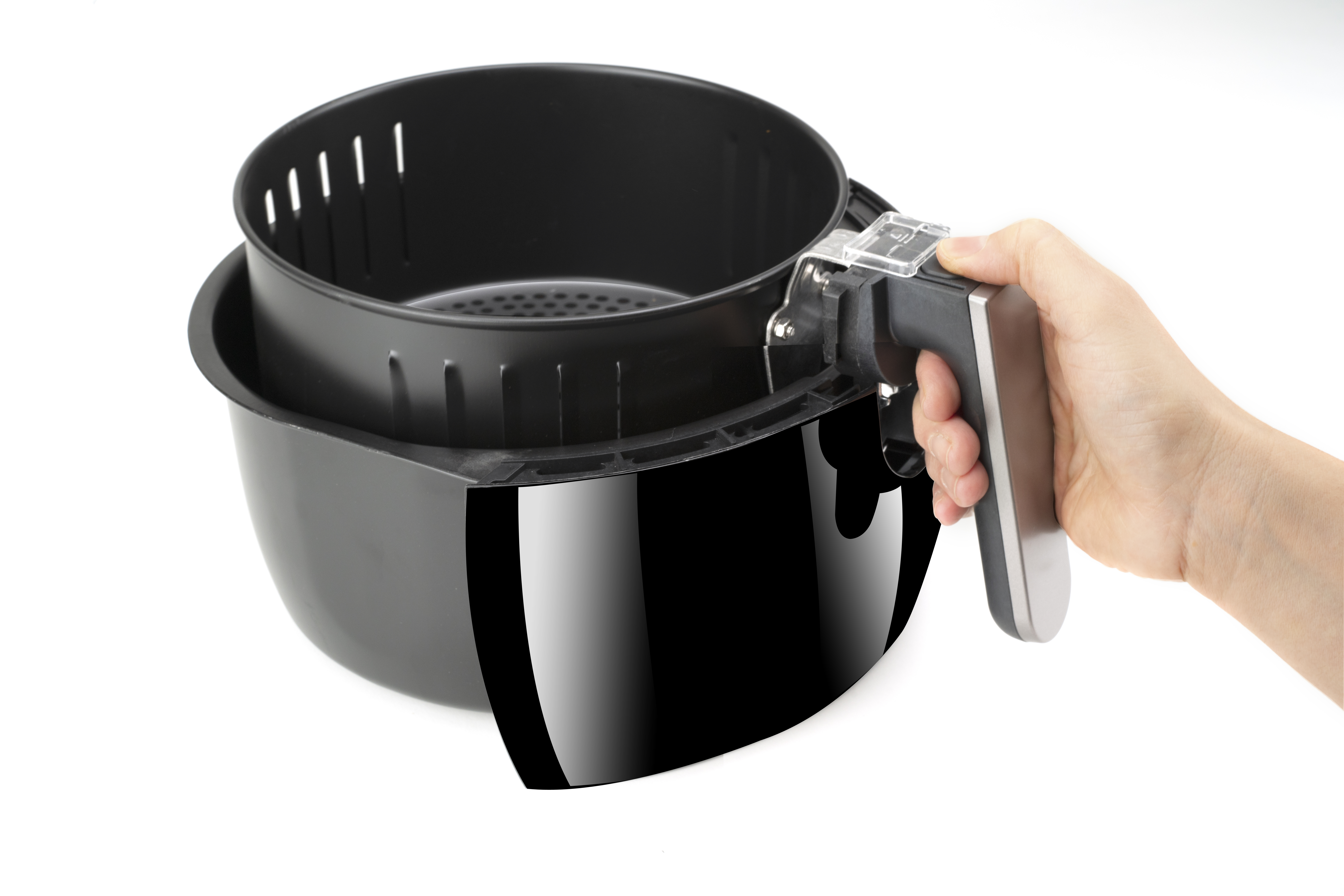 Czarny kosz do frytkownicy powietrznej trzymany ręką. Białe tło. Błyszczące czarne urządzenie.