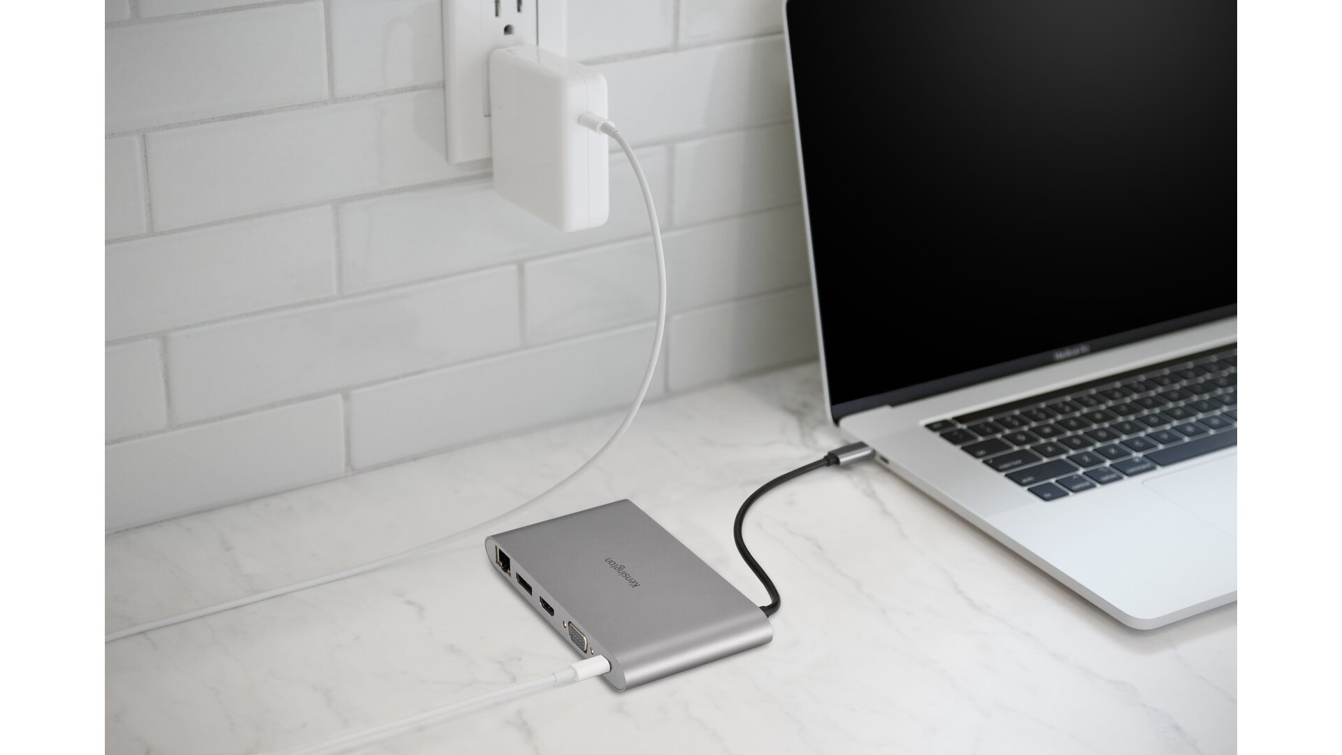Laptop mit silbernem Hub verbunden, Netzteil in der Wand.