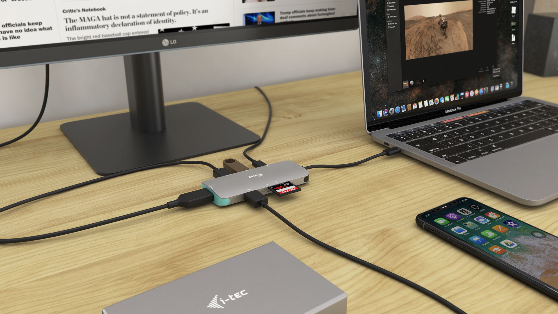 Un laptop, un telefono, un hub USB e un disco rigido sono collegati su un tavolo di legno.