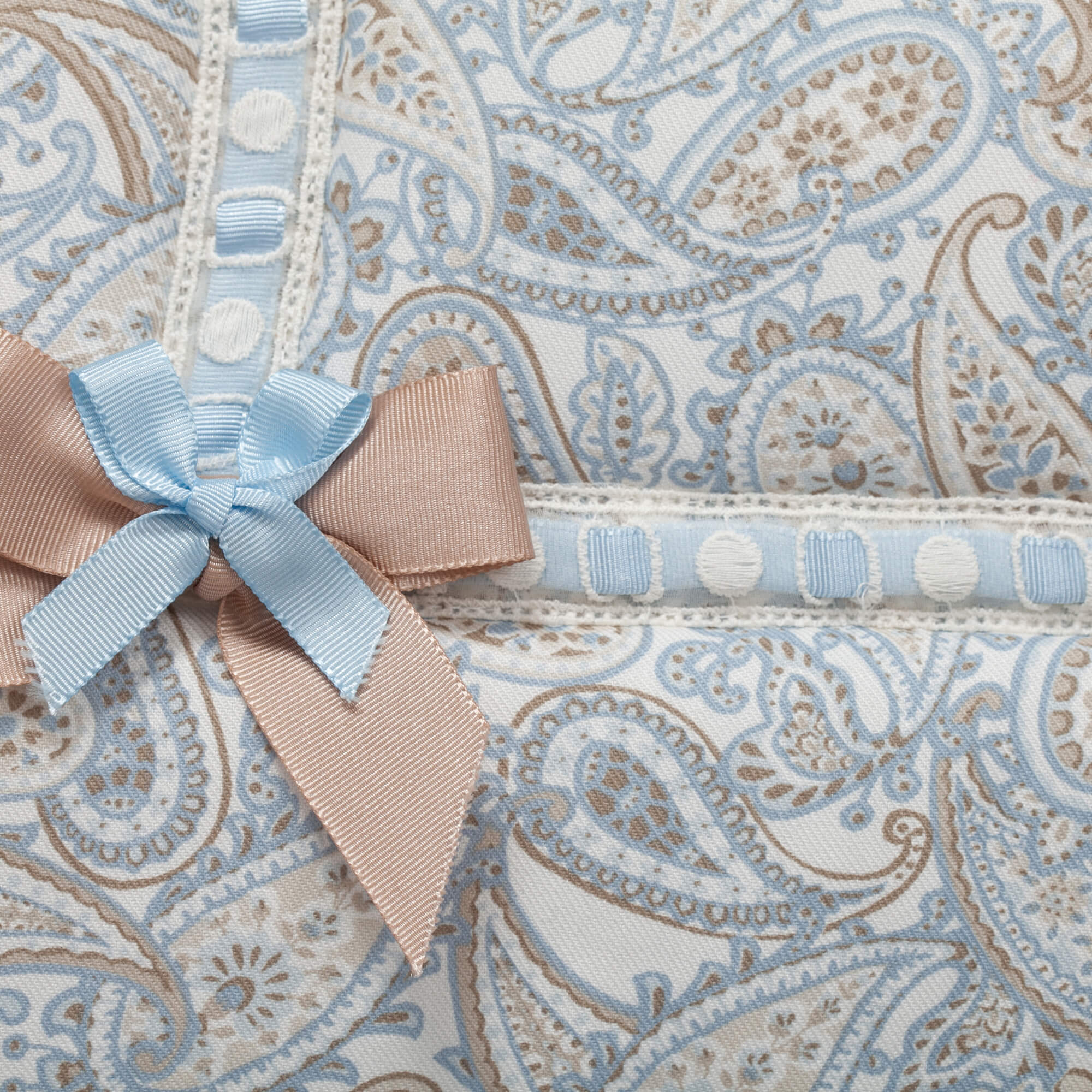 Primer plano de una tela estampada. Un lazo azul está a la izquierda, con detalles blancos y marrones.