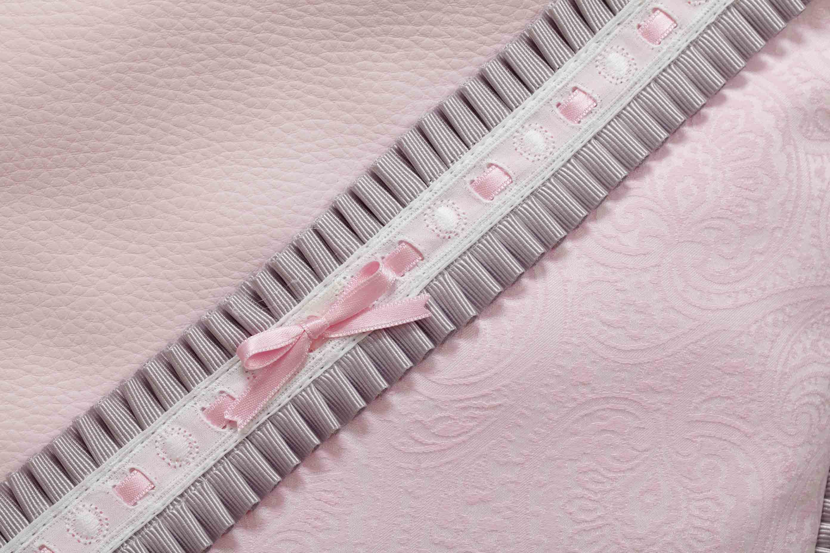 Tela rosa con detalle de cinta. La cinta tiene un lazo rosa en el centro.