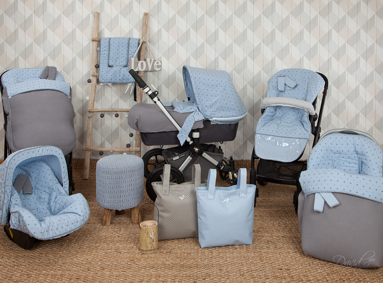 Un conjunto de artículos para bebés con un patrón de estrellas azules: cochecito, asiento de coche, bolsos y accesorios. En una alfombra.