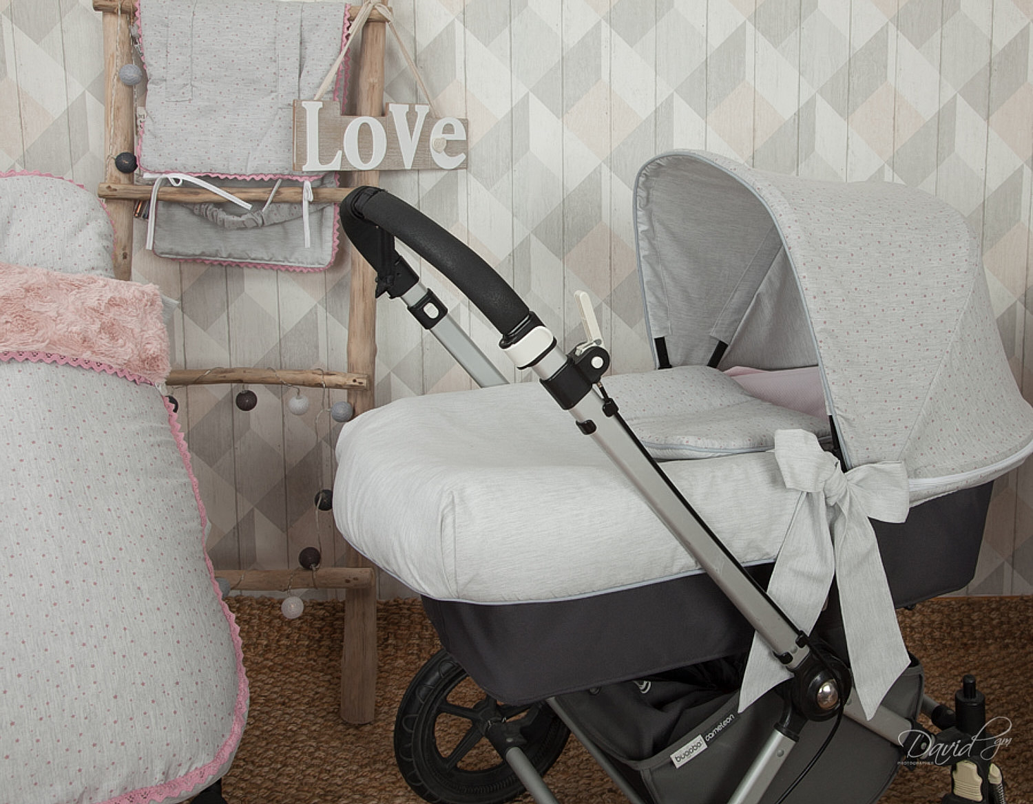 Un cochecito de bebé con un patrón de puntos gris y blanco, con una escalera de madera y la palabra 'Love'.