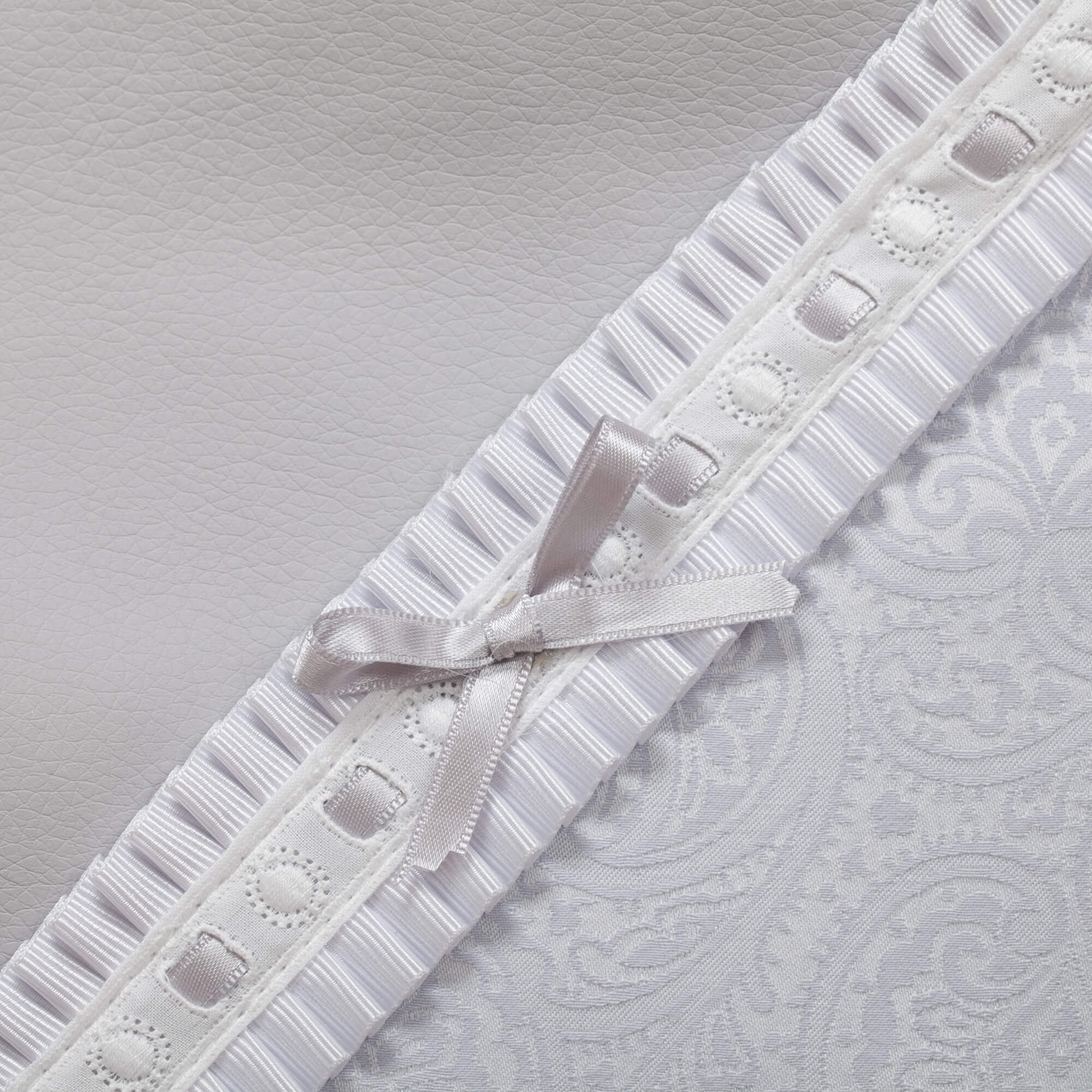 Primer plano de una tela blanca con un patrón floral y un lazo decorativo.