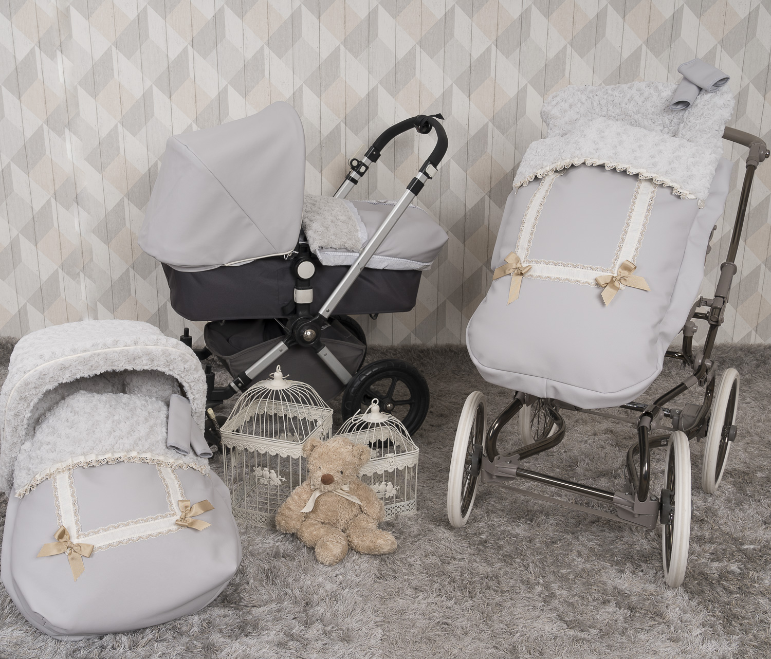 Juego de cochecito con accesorios sobre superficie gris. Pared estampada en el fondo.