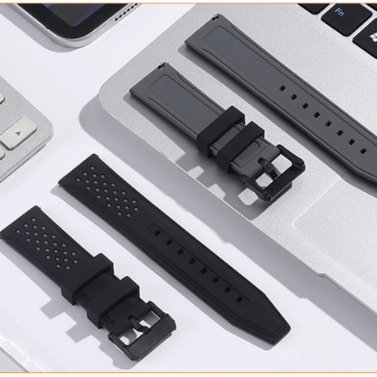 Cinturini per orologi in nero e grigio, su una tastiera del laptop.