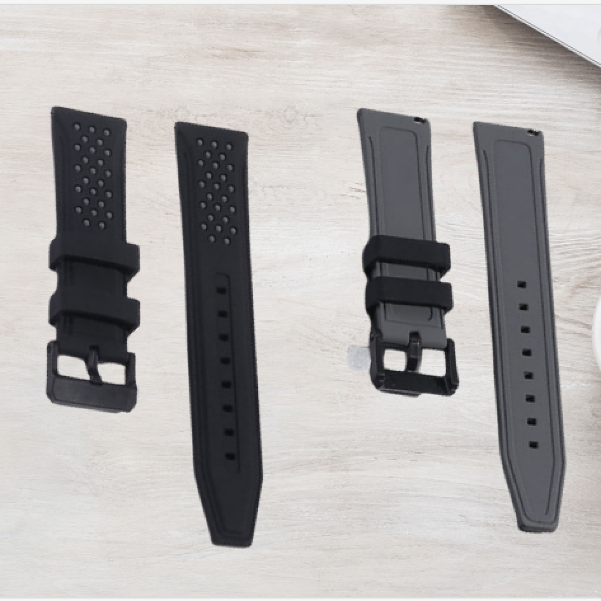 Quattro cinturini di orologi di diversi design. Due sono neri, due grigi, con superficie strutturata e fibbie metalliche.