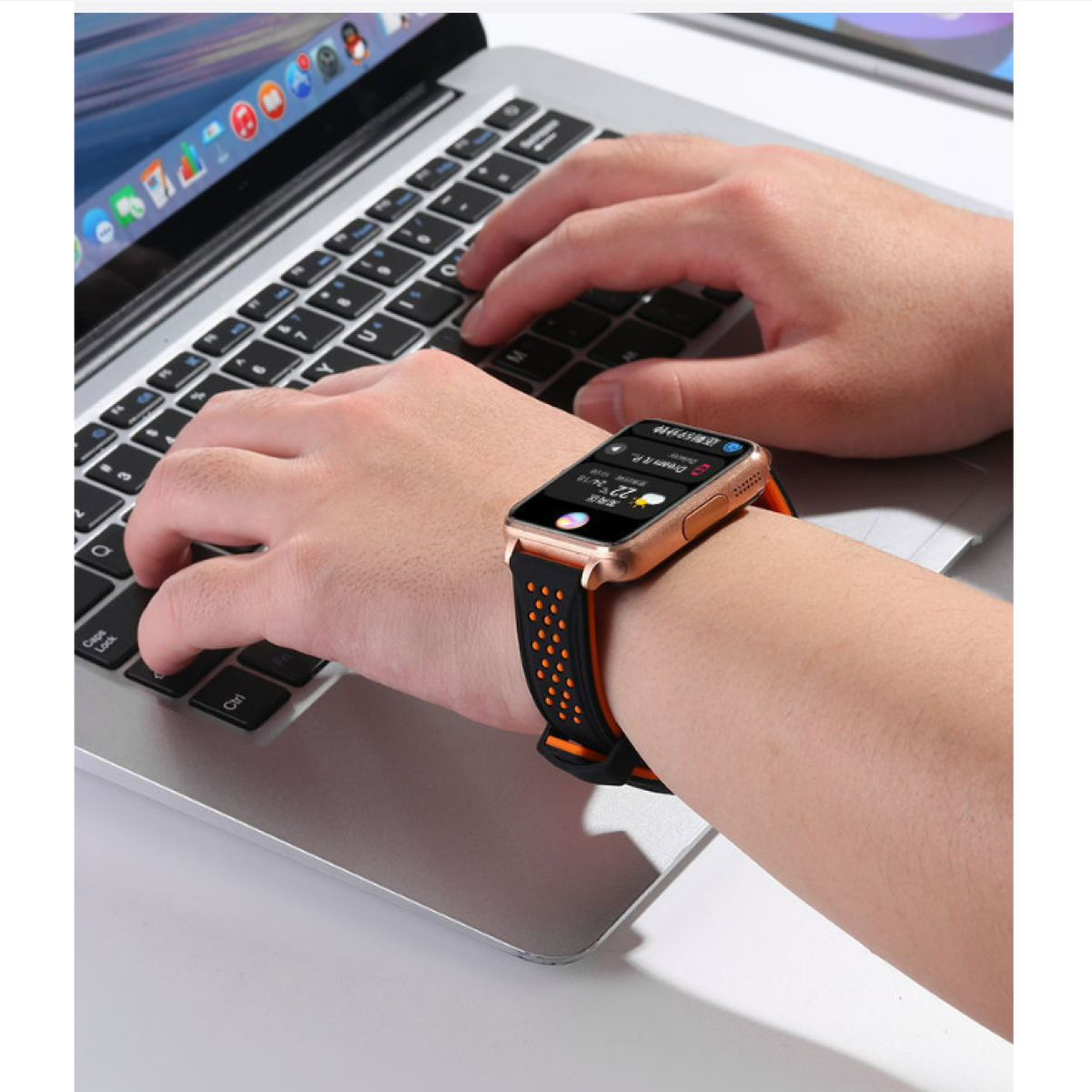 Una persona che usa un laptop e indossa uno smartwatch con un cinturino arancione e nero.