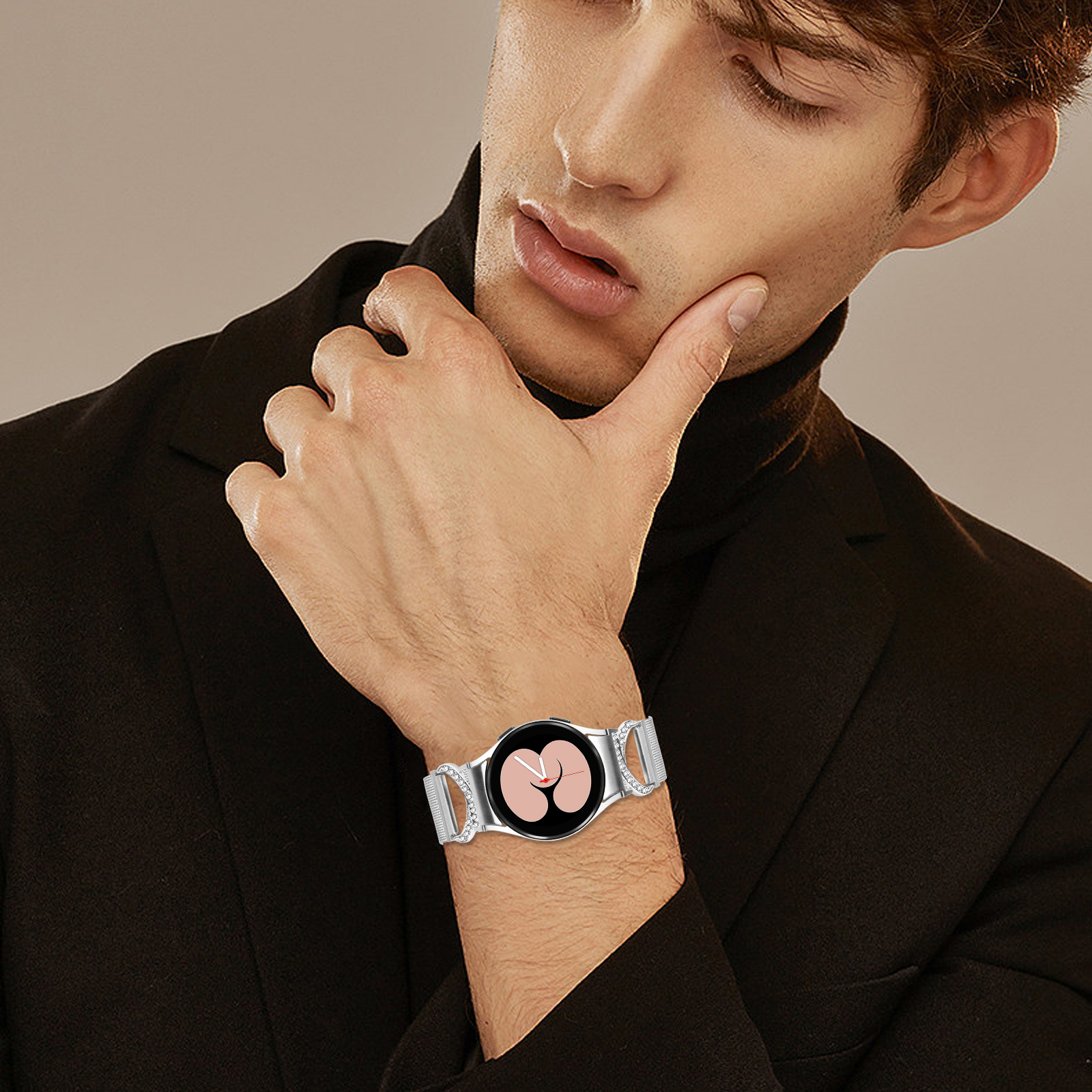 Un uomo con un dolcevita nero e un orologio. L'orologio ha un quadrante rotondo e un cinturino in metallo.