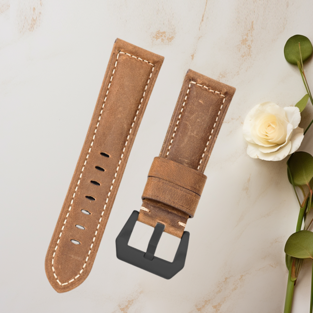 Cinturini in pelle marrone con cuciture bianche e fibbia nera. Fiore bianco e foglie.