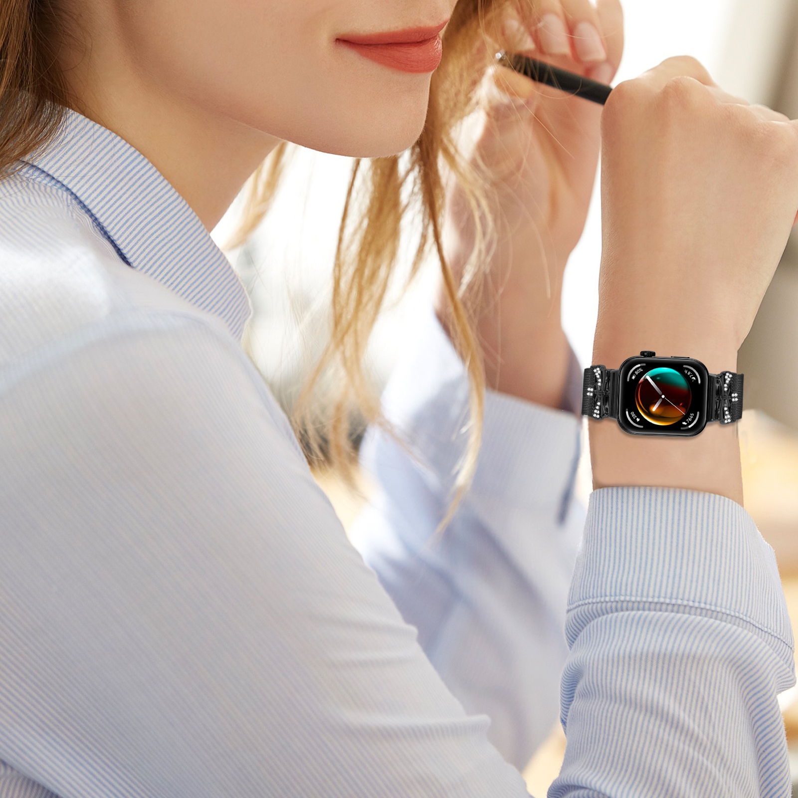 Una donna che indossa uno smartwatch, tiene una penna. L'orologio mostra dati.