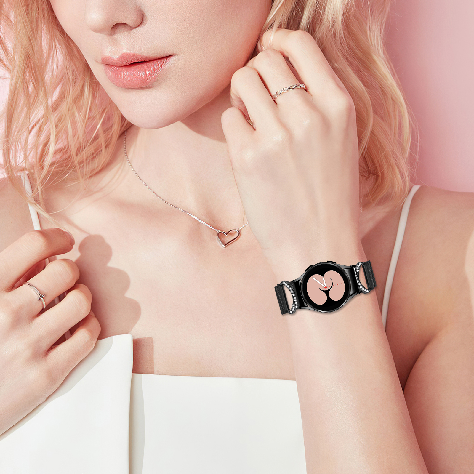 Frau, die eine schwarze Smartwatch mit herzförmiger Anhängerkette und Ringen trägt.